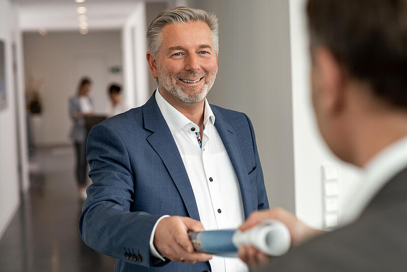 Geschäftsführer Thomas Gugau, der lächelnd Unterlagen entgegennimmt